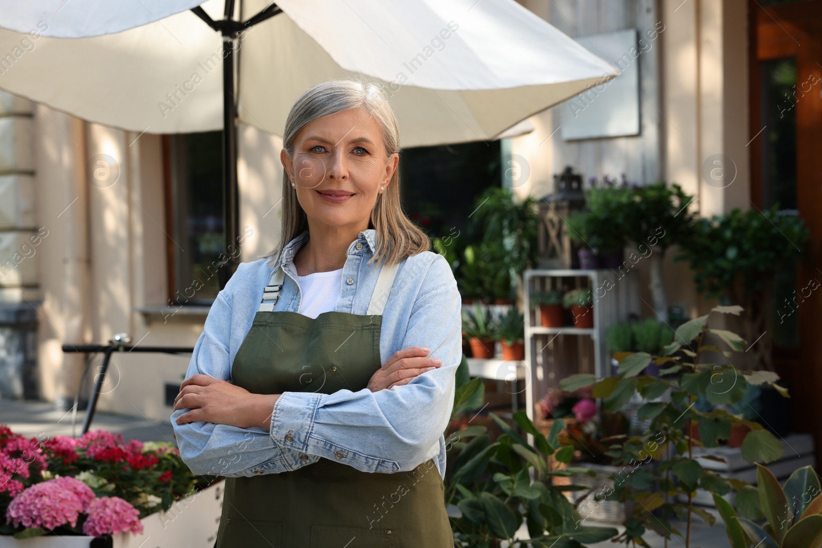 Photo of Portrait of smiling business owner near her flower shop outdoors, space for text