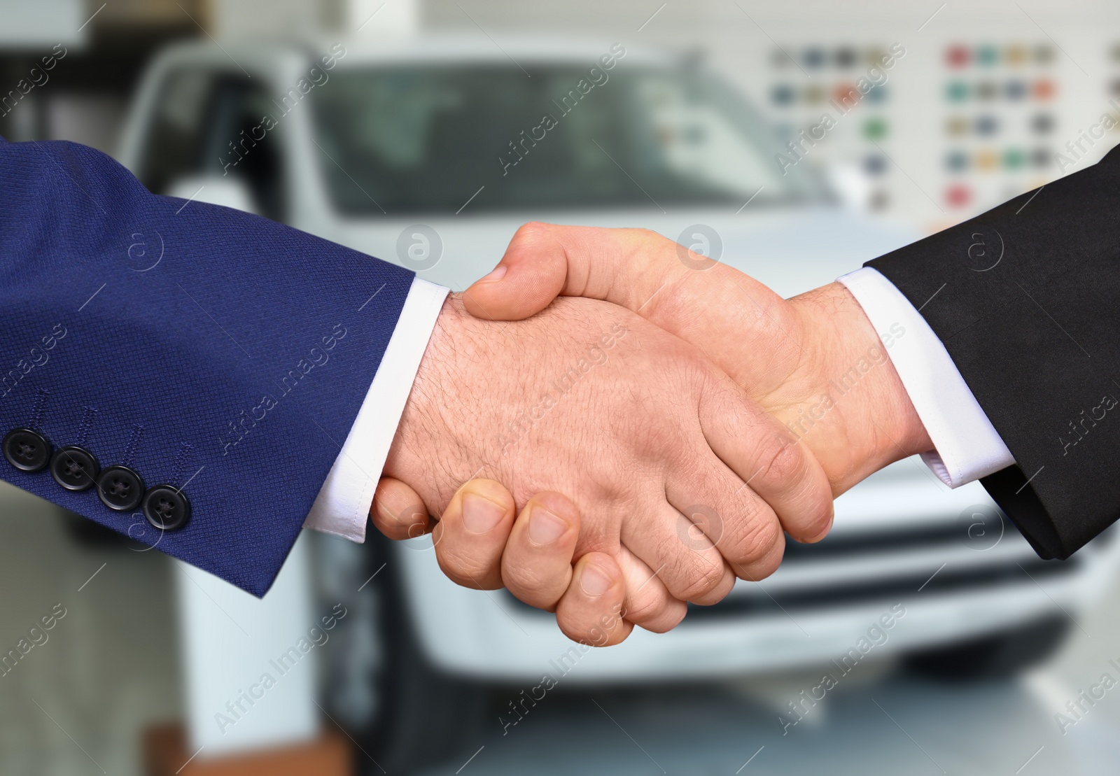 Image of Man buying car and shaking hands with salesman against blurred auto, closeup