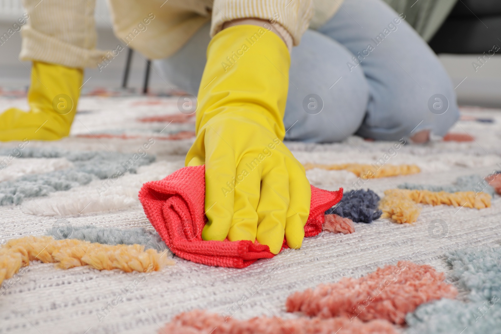 Photo of Woman in rubber gloves cleaning carpet with rag indoors, closeup