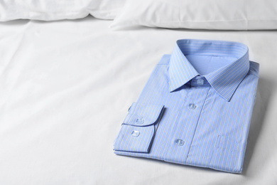 Stylish light blue shirt on bed, space for text. Dry-cleaning service