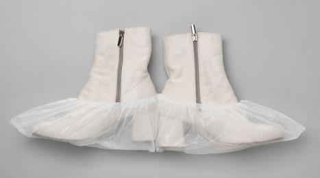 Photo of Women's boots in shoe covers on grey background, top view