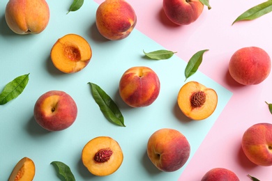 Photo of Fresh ripe peaches and green leaves on color background, flat lay