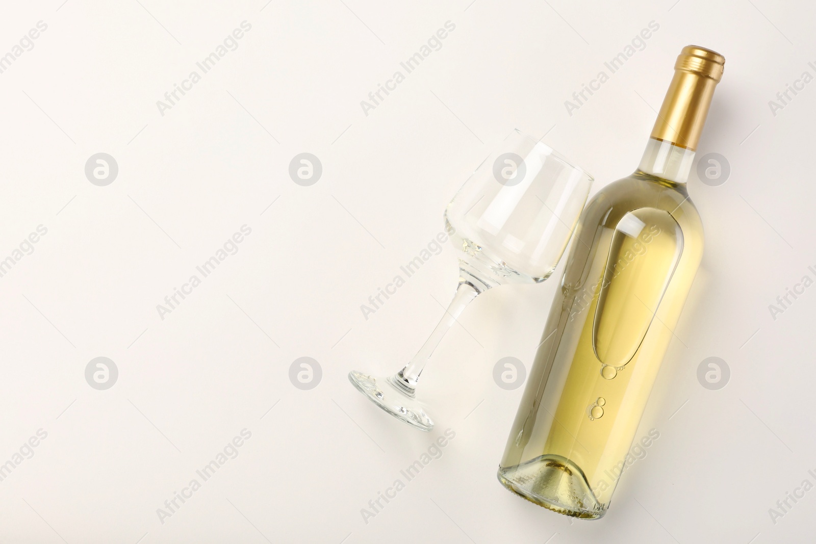 Photo of Bottle of expensive white wine and wineglass on light background, top view. Space for text