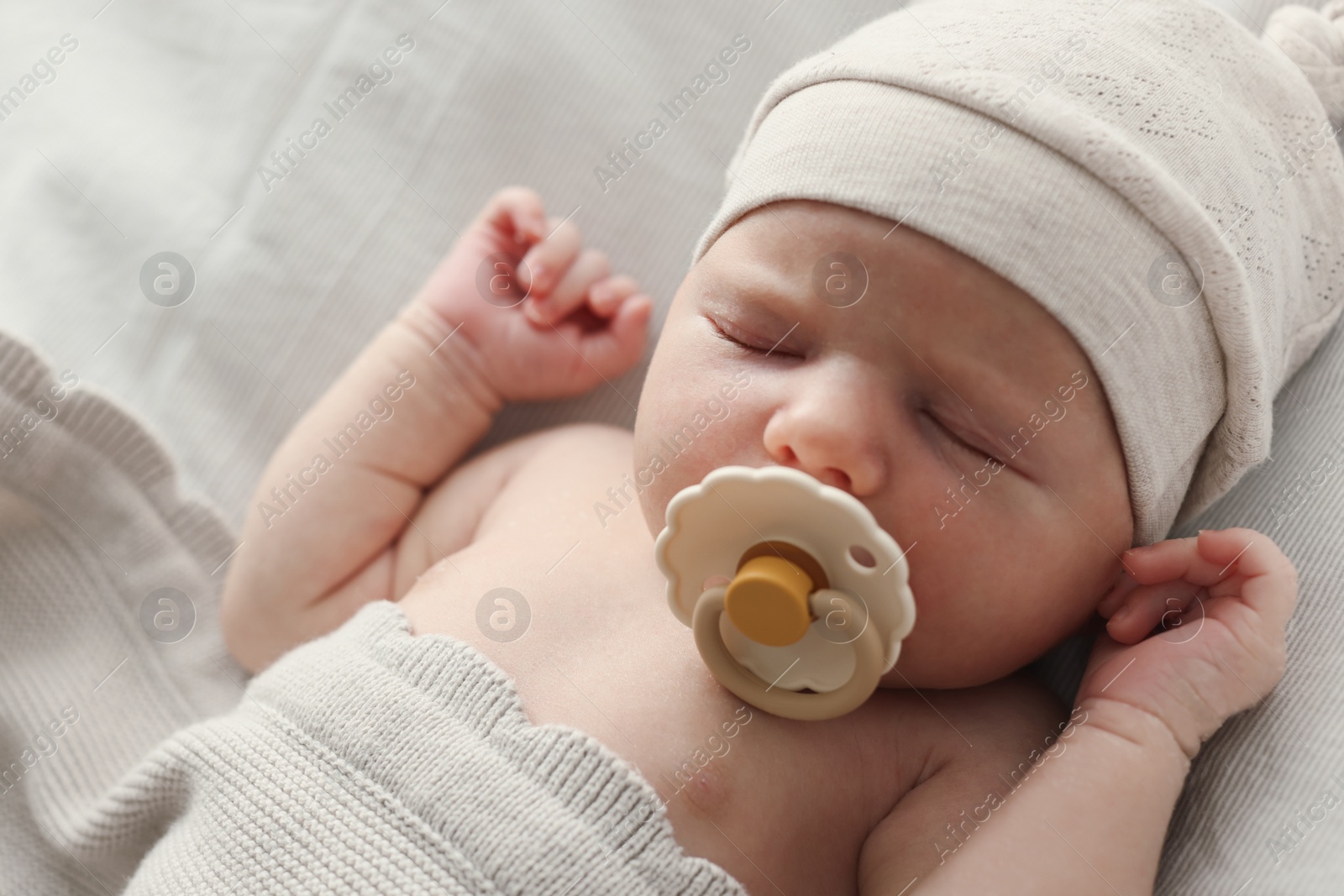 Photo of Adorable little baby with pacifier sleeping in bed, closeup