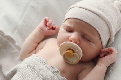 Photo of Adorable little baby with pacifier sleeping in bed, closeup