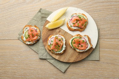 Tasty canapes with salmon served on wooden table, top view