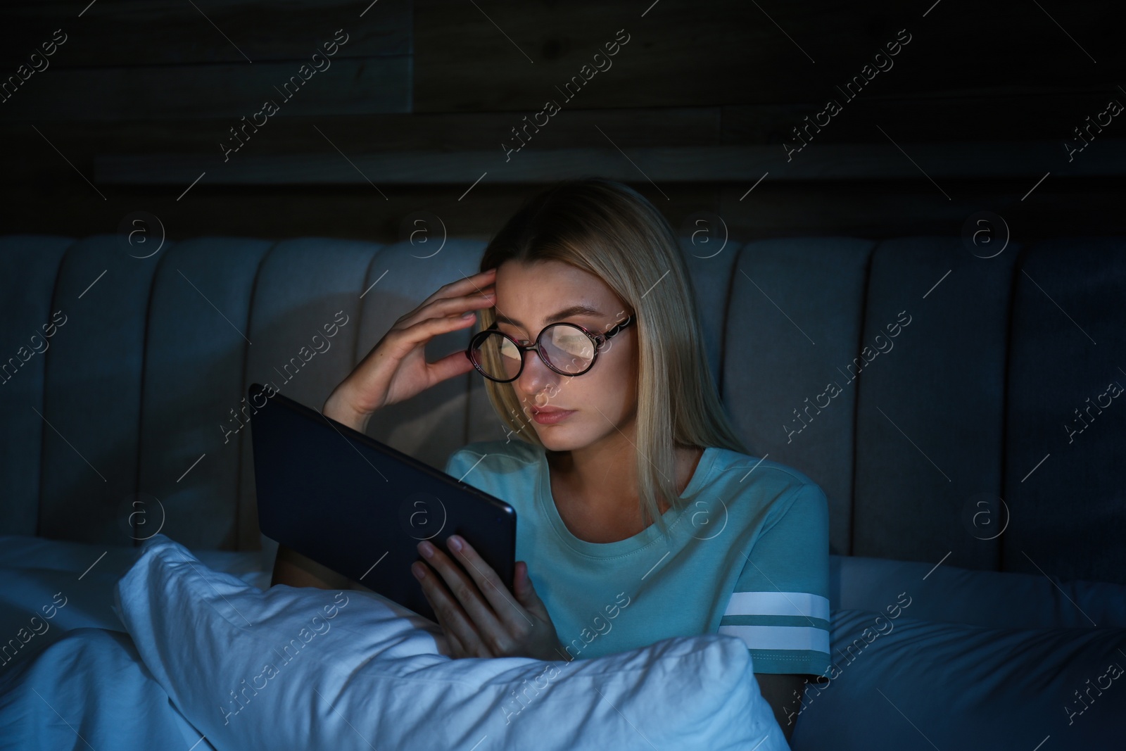 Photo of Young woman using tablet in bed at night. Sleeping disorder problem