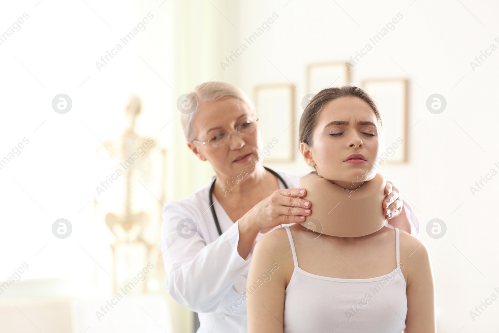 Photo of Female orthopedist applying cervical collar onto patient's neck in clinic