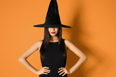 Photo of Beautiful woman wearing witch costume for Halloween party on yellow background