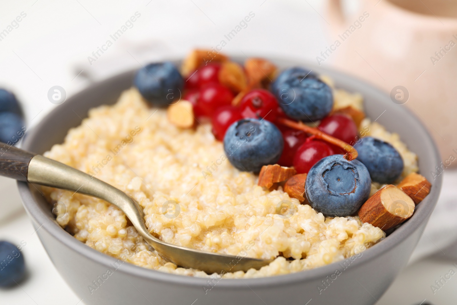 Photo of Bowl of delicious cooked quinoa with almonds, cranberries and blueberries, closeup