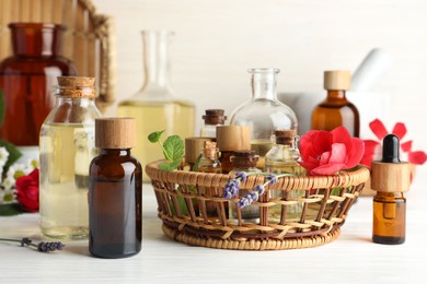 Aromatherapy. Different essential oils and flowers on white wooden table