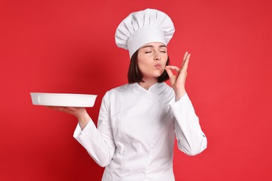 Photo of Confectioner with baking dish showing ok gesture on red background