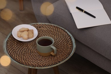 Cup of drink and cookies on coffee table near sofa indoors