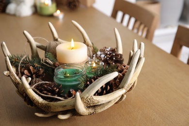 Photo of Burning scented conifer candles with Christmas decor on wooden table indoors