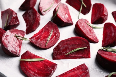 Raw beetroot slices and rosemary on parchment, closeup