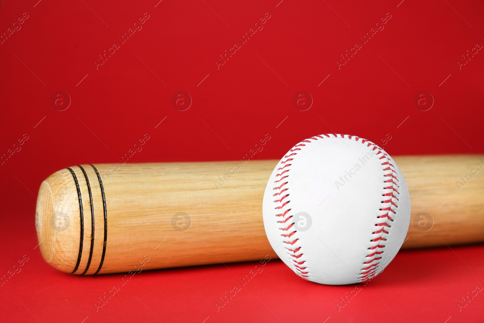 Photo of Wooden baseball bat and ball on red background. Sports equipment