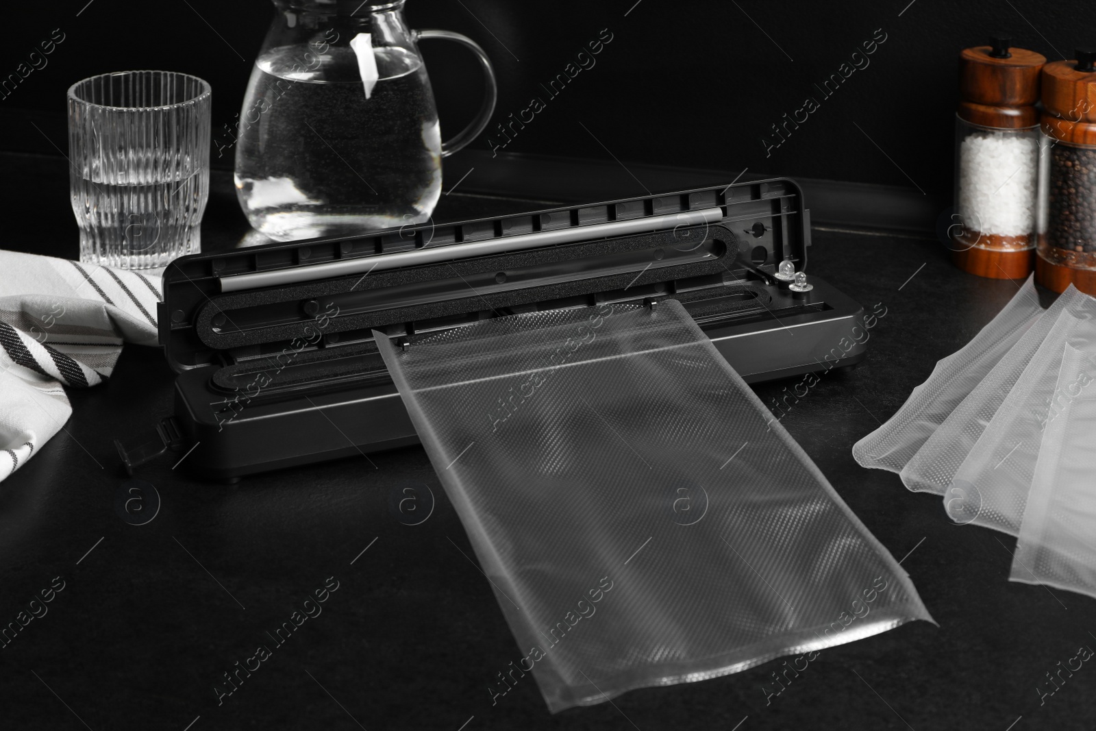 Photo of Sealer for vacuum packing with plastic bags on black kitchen countertop