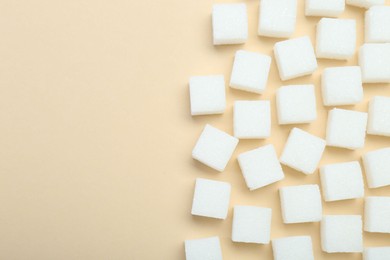 White sugar cubes on beige background, top view. Space for text