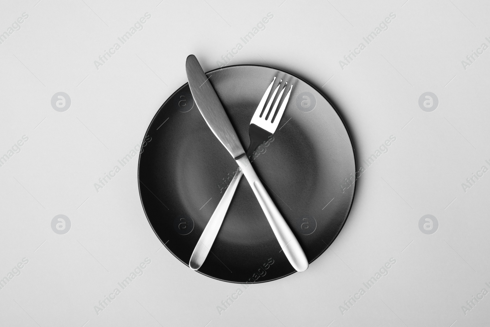 Photo of Empty plate with cutlery on light background, flat lay