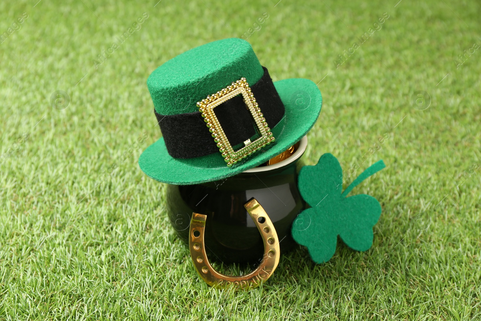 Photo of St. Patrick's day. Pot of gold with leprechaun hat, horseshoe and decorative clover leaf on green grass