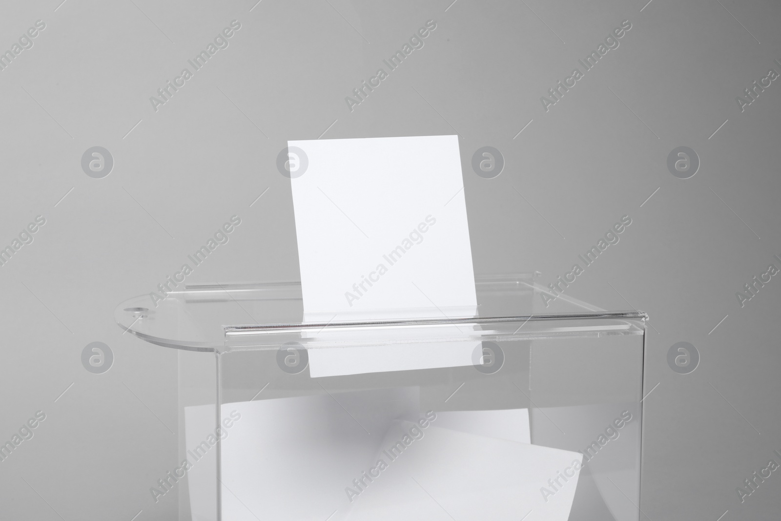 Photo of Ballot box with votes on light grey background. Election time