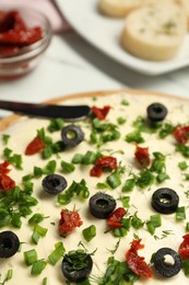 Photo of Fresh butter board with cut olives and onion on white table, closeup