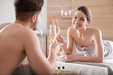 Photo of Romantic young couple with champagne in spa salon