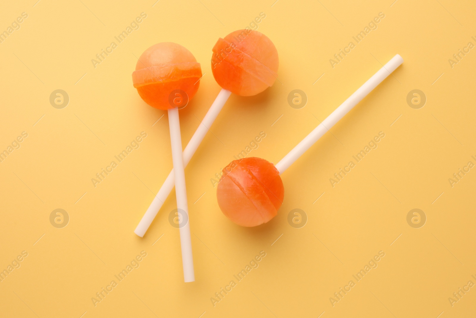 Photo of Tasty lollipops on yellow background, flat lay