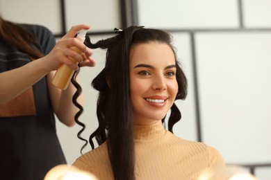 Photo of Hair styling. Professional hairdresser working with smiling client in salon, closeup