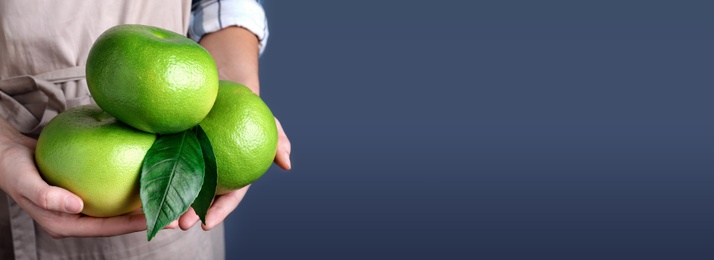 Image of Woman holding sweetie fruits on blue background, closeup view with space for text. Banner design