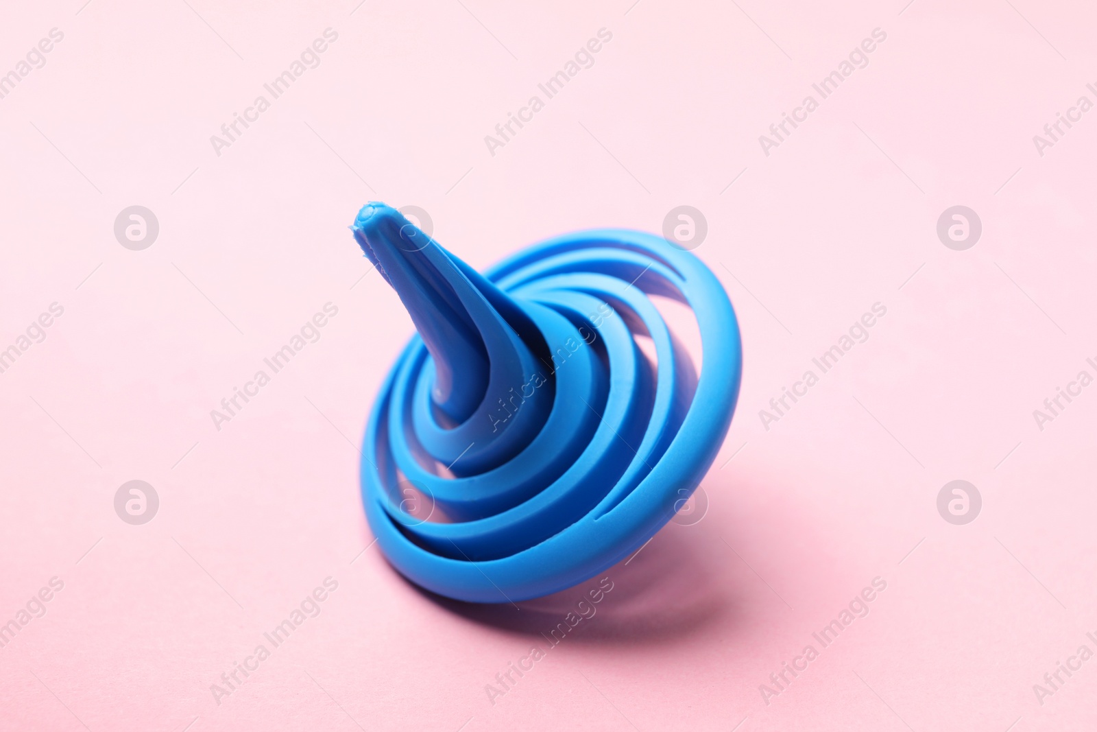 Photo of One blue spinning top on pink background, closeup