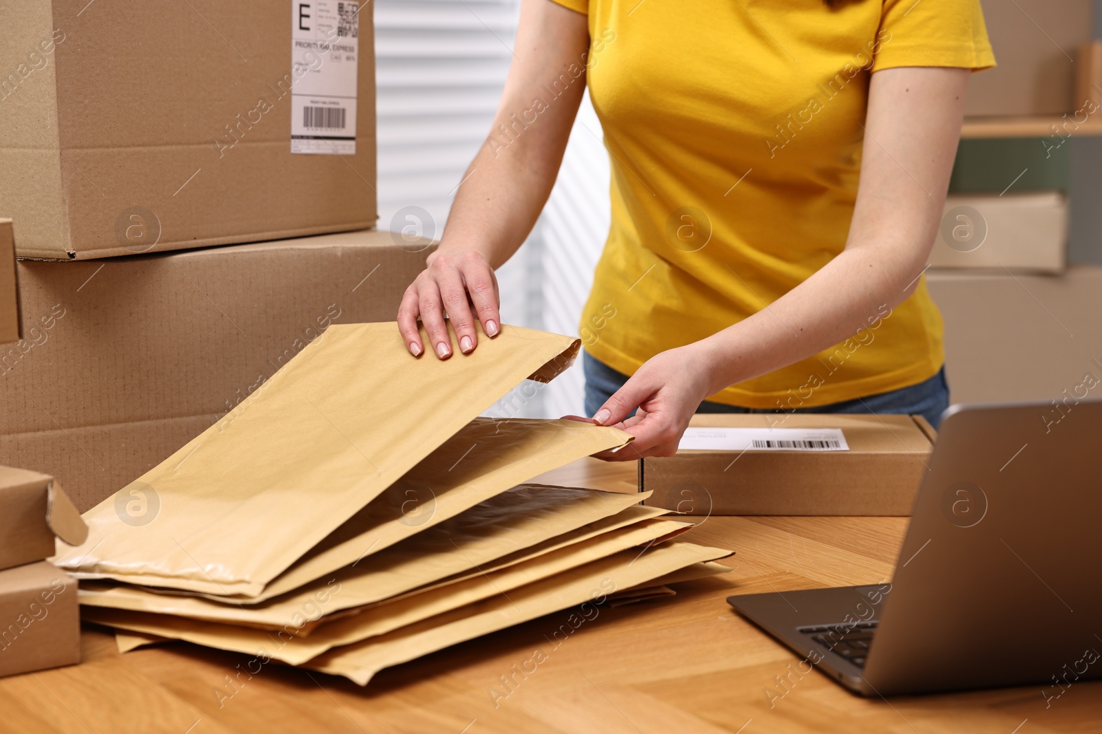 Photo of Parcel packing. Post office worker with parcels at wooden table indoors, closeup