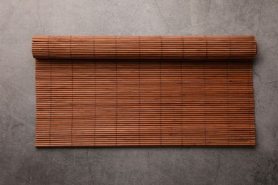 Photo of Rolled bamboo mat on grey table, top view. Space for text