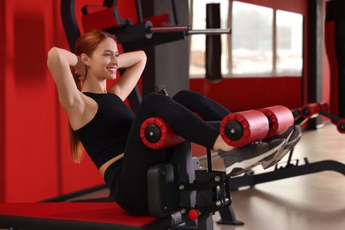 Athletic young woman pumping up abs on roman chair in gym