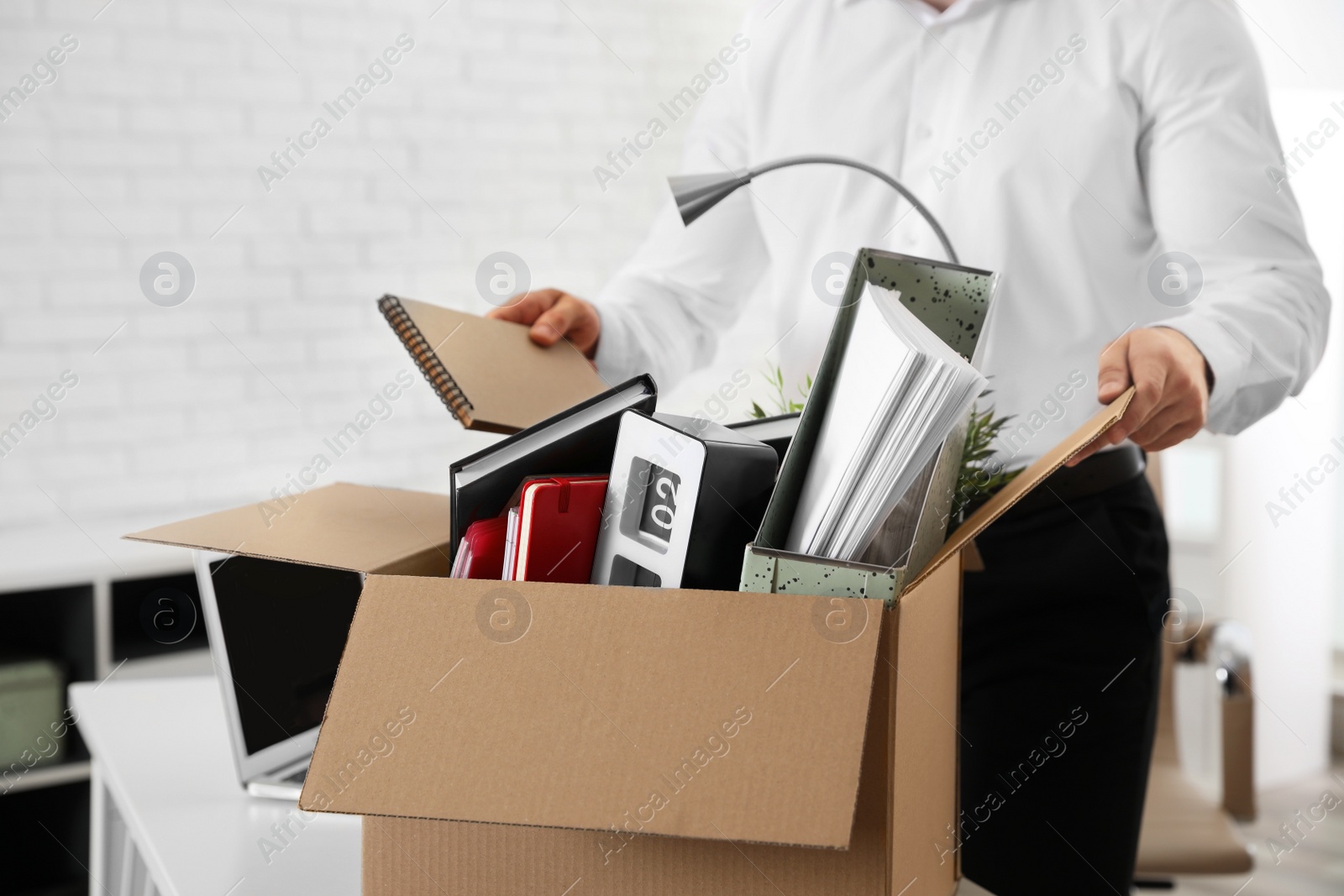 Photo of Young man packing stuff in box at office, closeup