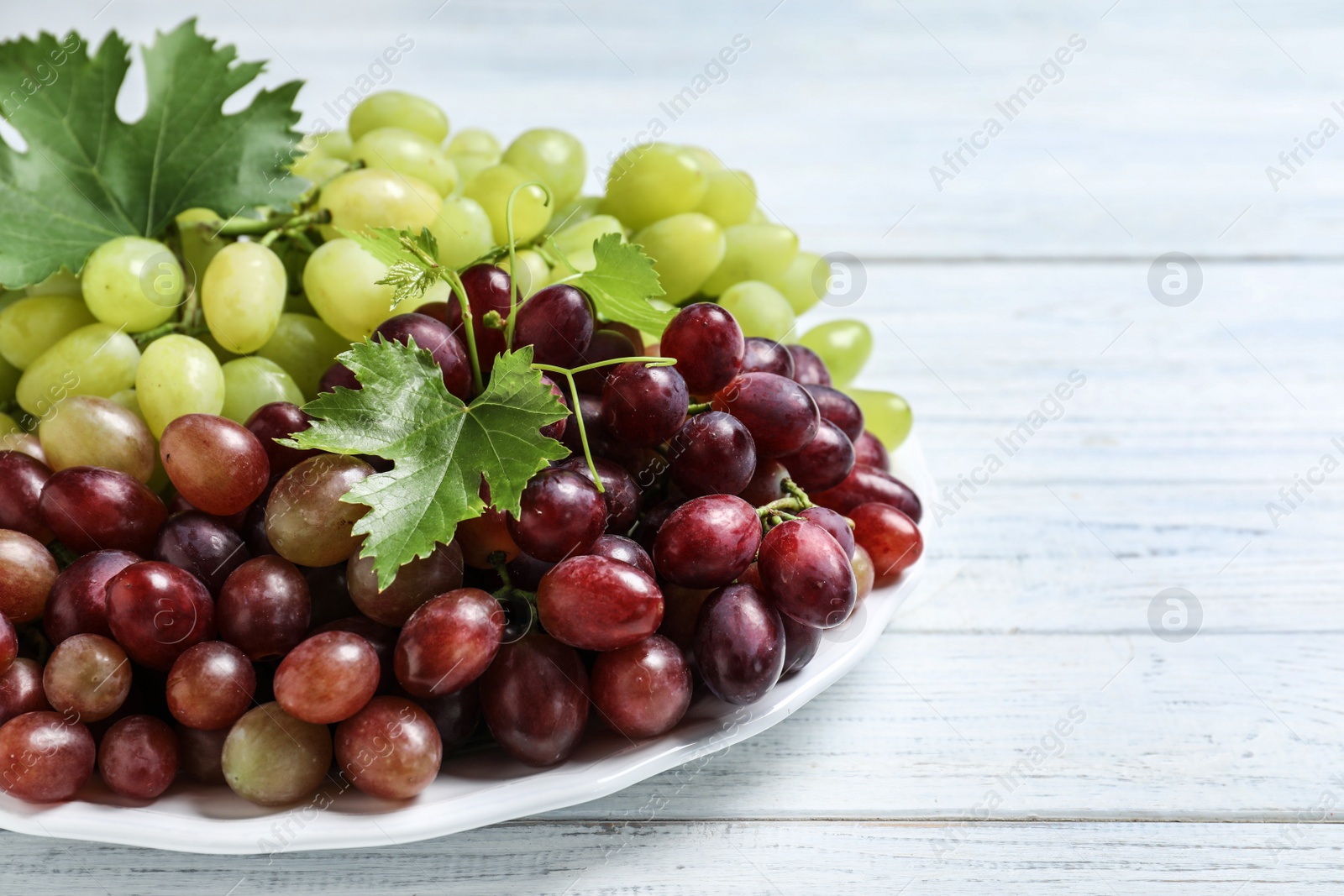 Photo of Fresh ripe juicy grapes on white wooden table