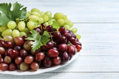 Fresh ripe juicy grapes on white wooden table