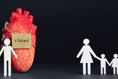 Photo of Divorce concept. Heart model, card with word Closed near paper figures of man, woman and children on black background. Space for text