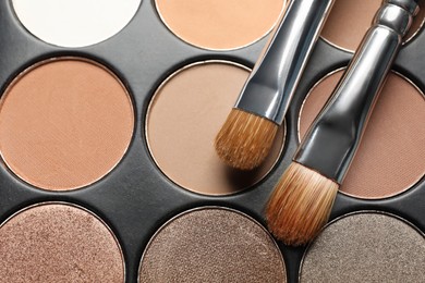 Photo of Beautiful eye shadow palette and brushes as background, top view