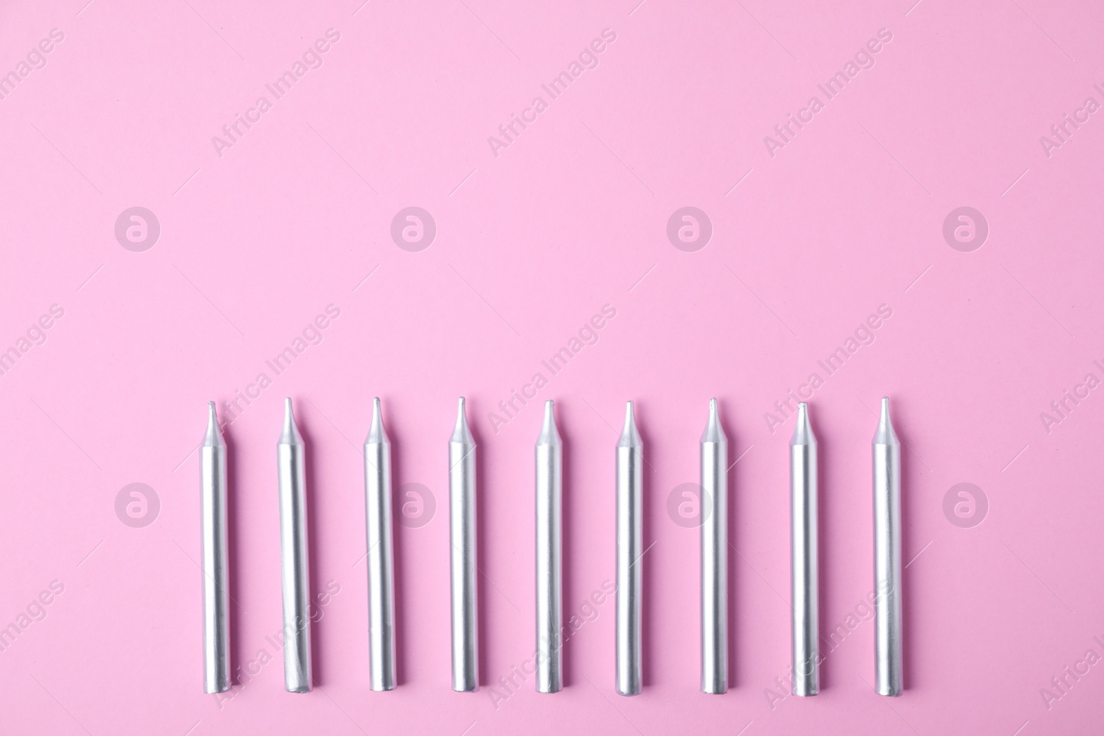 Photo of Silver birthday candles on pink background, top view with space for text