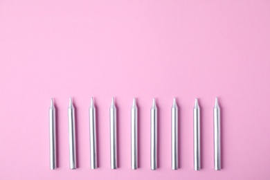 Photo of Silver birthday candles on pink background, top view with space for text