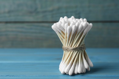 Photo of Many cotton buds on light blue wooden table, space for text