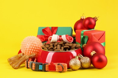 Photo of Different pet goods with Christmas gifts on yellow background. Shop assortment
