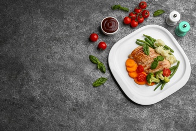 Photo of Tasty grilled chicken fillet with vegetables and sauce on grey table, flat lay. Space for text