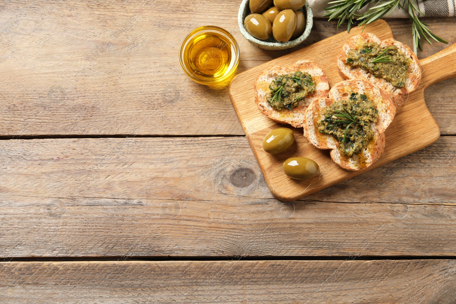 Photo of Tasty bruschettas with pesto and rosemary on wooden table, flat lay. Space for text