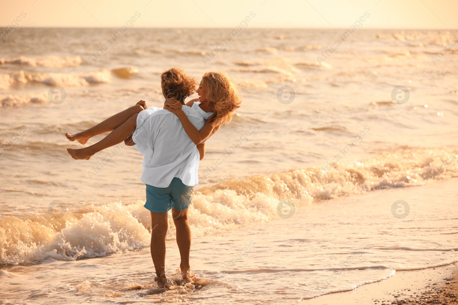 Photo of Young couple having fun on beach at sunset