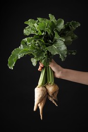 Woman holding sugar beets on black background, closeup