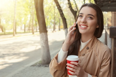 Photo of Young woman talking by phone outdoors on sunny day