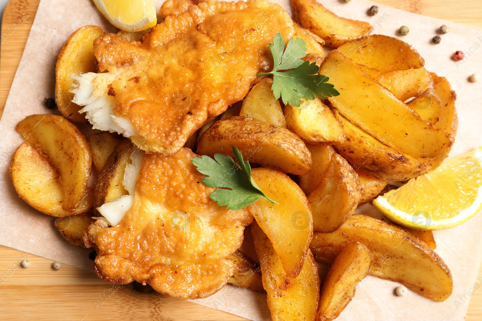 Photo of British traditional fish and potato chips on wooden background, closeup