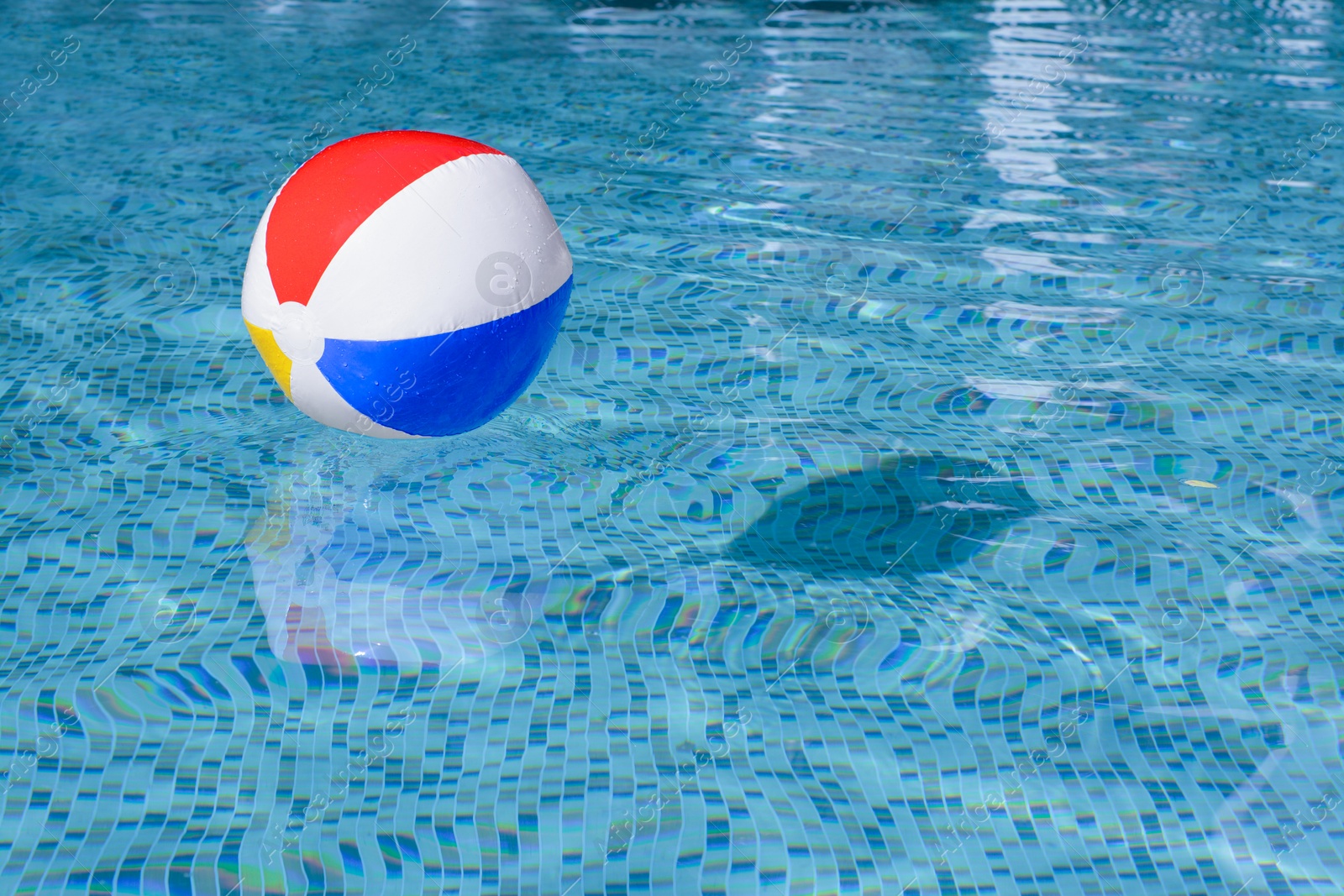 Photo of Inflatable beach ball floating in swimming pool, space for text